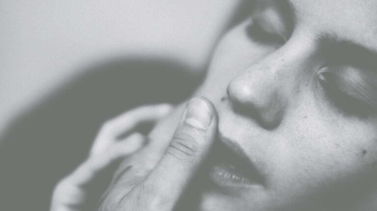 A woman rubs someone's thumbs against her lips seductively